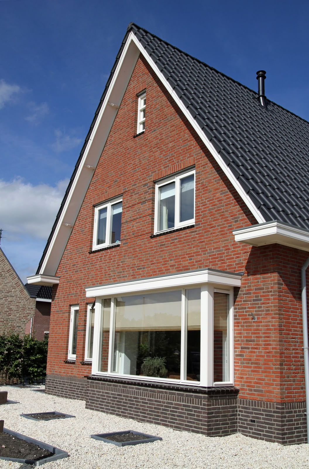 Nieuwbouwwoning met wit geschilderde kozijnen, boeidelen en dakranden